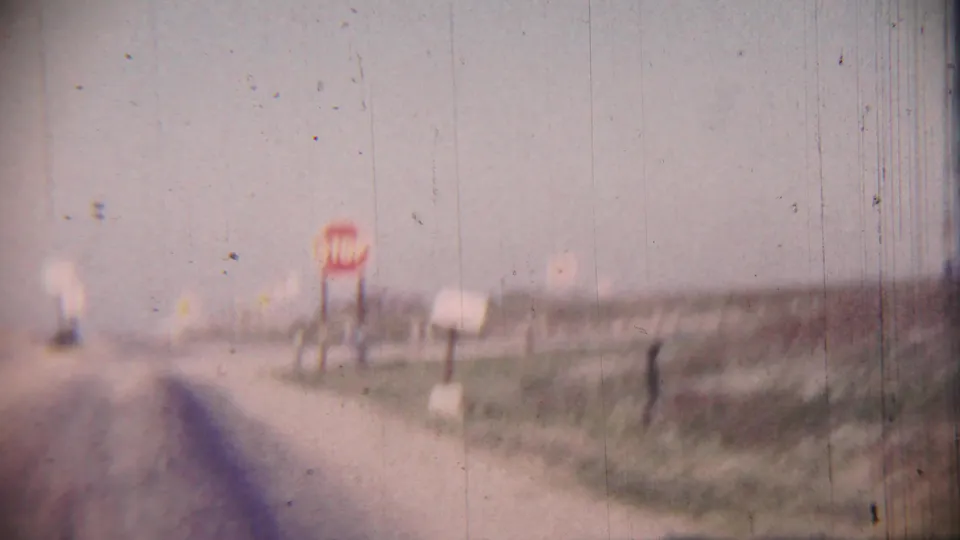 Soft 1959 Cheyenne County, Kansas road view with a red stop sign, white roadside posts, distant signs, open fields, and visible film wear.