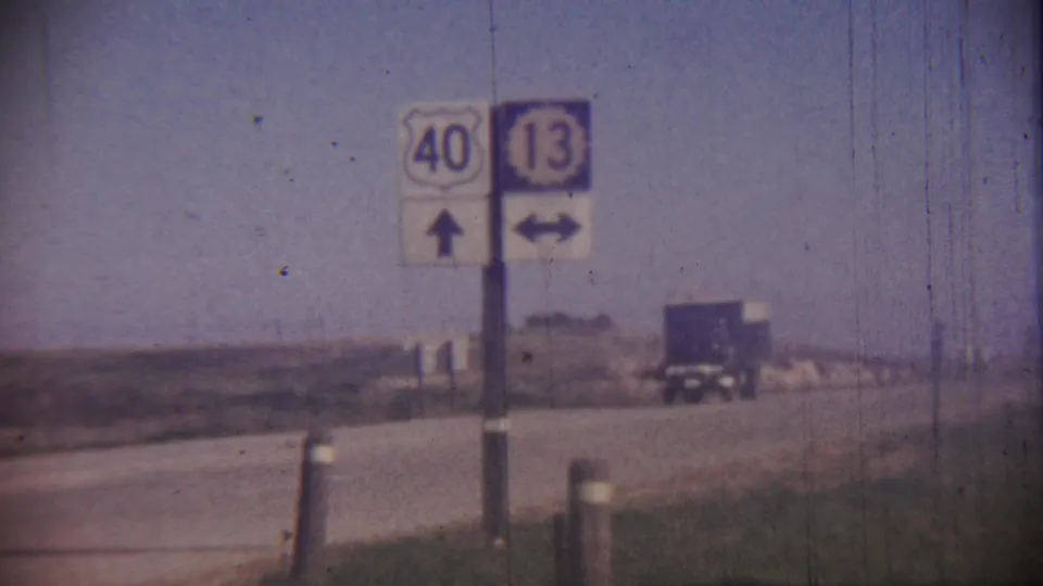 1959 Cheyenne County, Kansas frame with U.S. 40 and route 13 signs, directional arrows, open fields, and a distant truck.