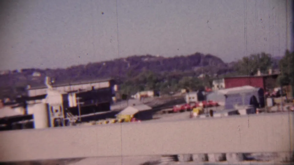 The final frame shows small buildings and parked vehicles in the supplied 1959 Cheyenne County, Kansas landscape clip, with hills in the background.