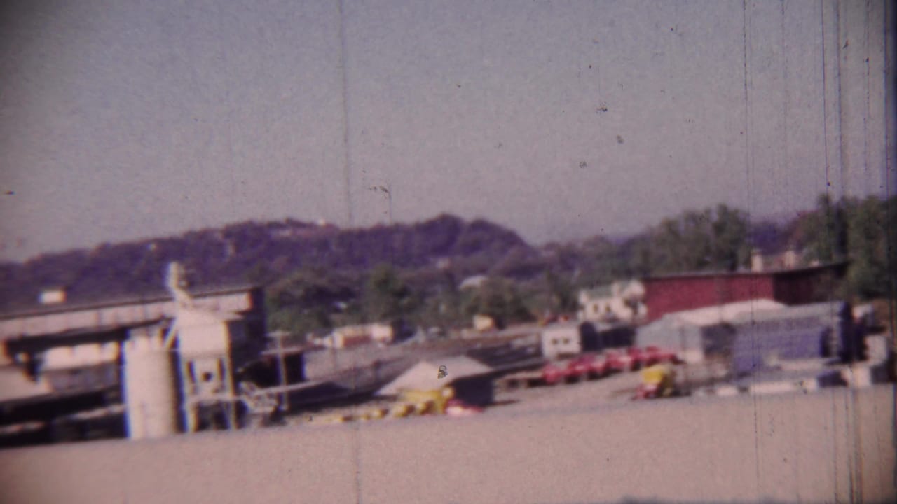 Street-level view of downtown buildings, parked cars, and a service station area.