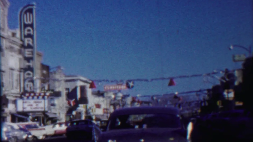 Saint Francis, Kansas in 1959 with a road-level view of cars, storefronts, overhead decorations, and the Wareham theater sign.