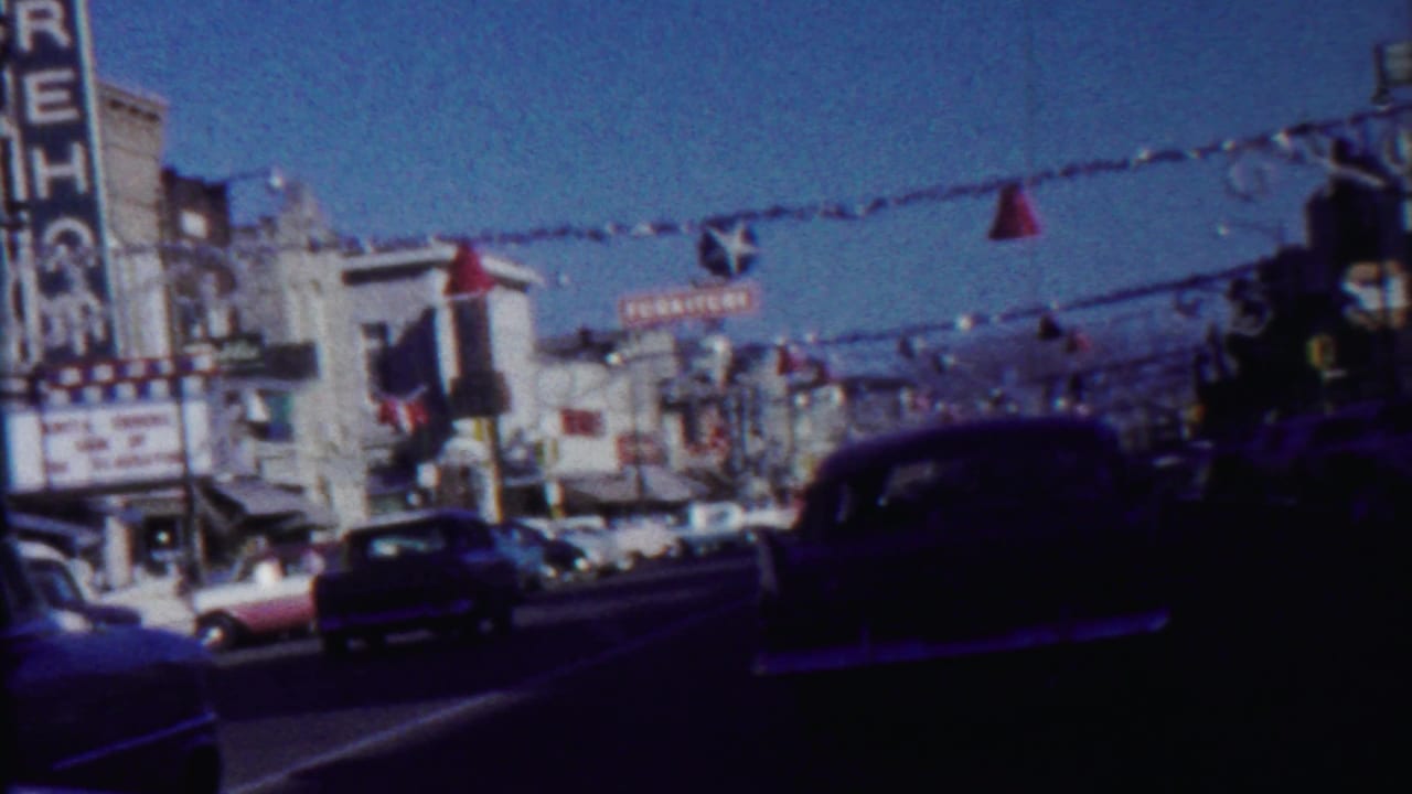 Saint Francis, Kansas commercial street with a dark mid-century car, visible theater signage, storefronts, and overhead decorations.