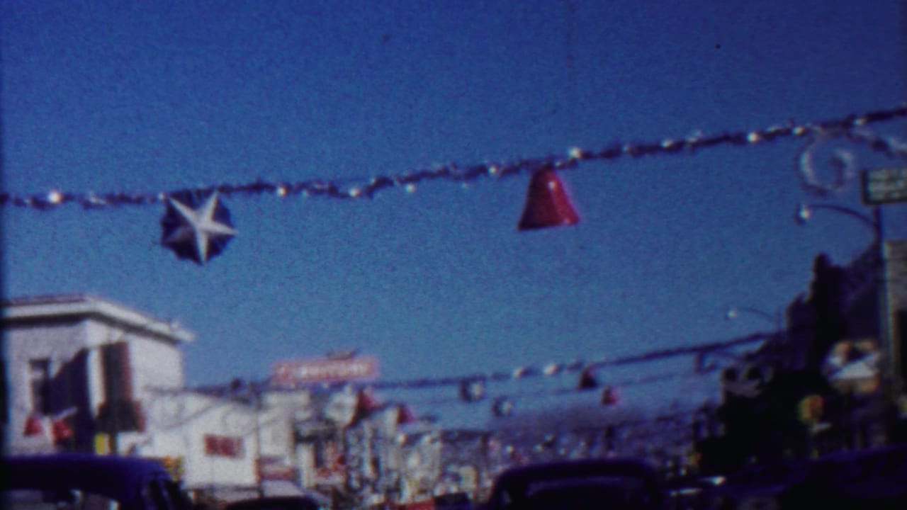 Street decorations hang above cars and storefronts, with a star ornament near the center of the frame.