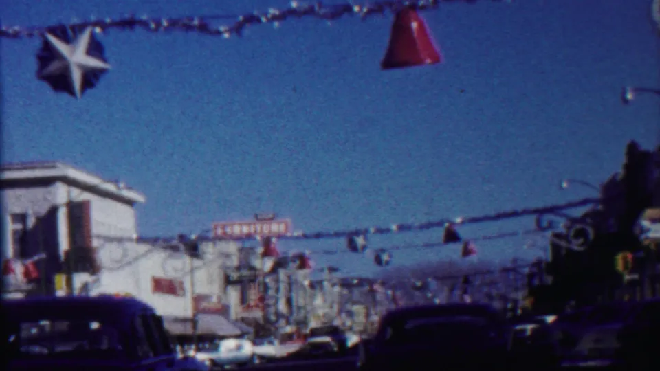 1959 Saint Francis, Kansas view of overhead star and bell decorations, storefront signs, traffic lights, and classic cars.