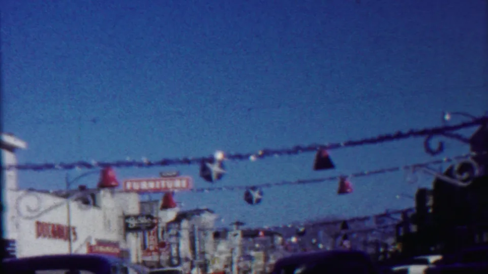 Saint Francis, Kansas, 1959 home-movie frame showing garlands and ornaments above a storefront-lined street.