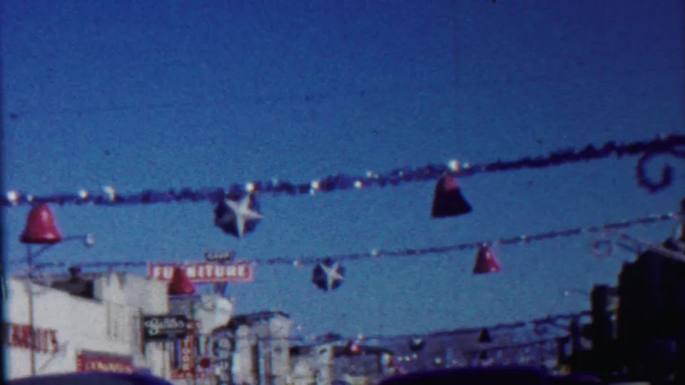 Saint Francis, Kansas street scene with festive hanging ornaments, storefront signage, utility lines, and deep blue 1959 8mm color.
