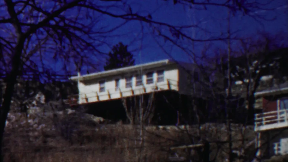 1959 8mm view of the modern hillside house, with the white upper level standing out above brush and rock.