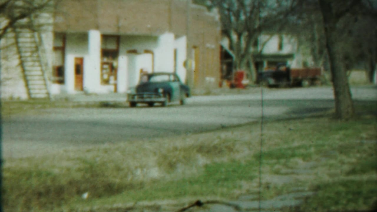Blue sedan near a brick building with white columns.