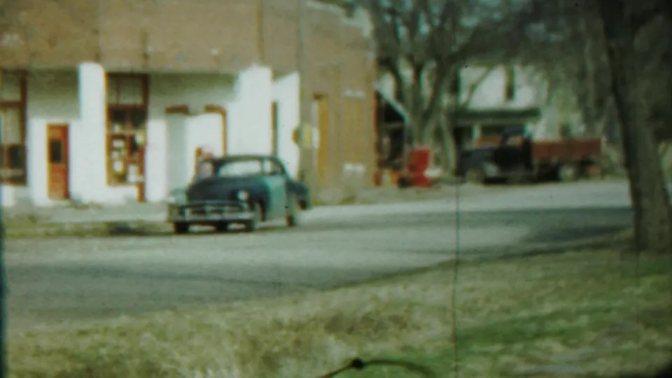 A blue mid-century car sits near a white and brown building on a quiet street in Saint Francis, Kansas, based on clip metadata.