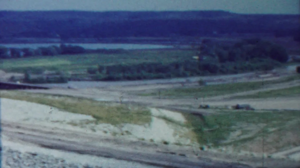 Saint Francis, Kansas 1959 frame with a soft 8mm view over fields, roads, trees, utility poles, and water on the horizon.