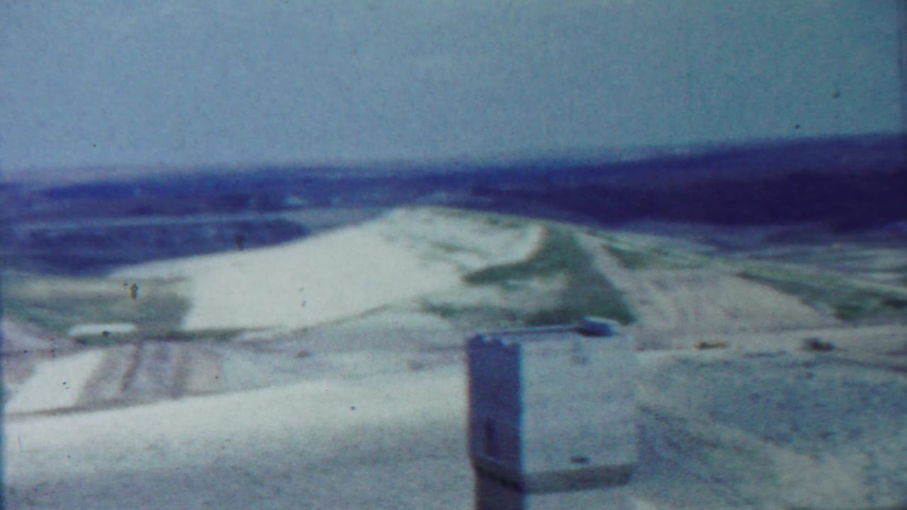 Tower near the lower foreground with white hills, green patches, and open sky beyond.