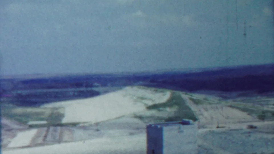 1959 Saint Francis, Kansas 8mm frame with rolling white terrain, green areas, distant horizon, and a tower partly visible at the bottom.
