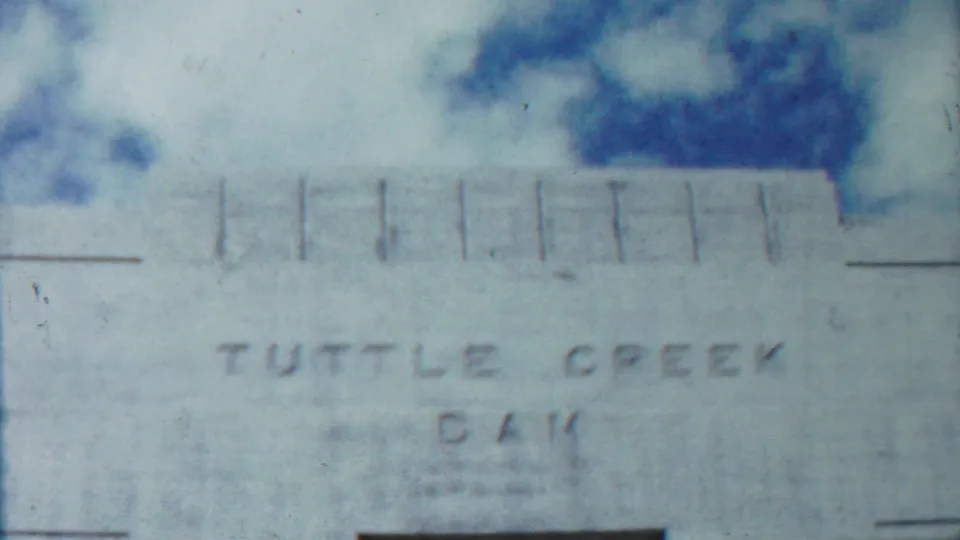 1959 Kansas frame of the Tuttle Creek Dam concrete facade, with engraved lettering, pale sky, and structural seams visible.
