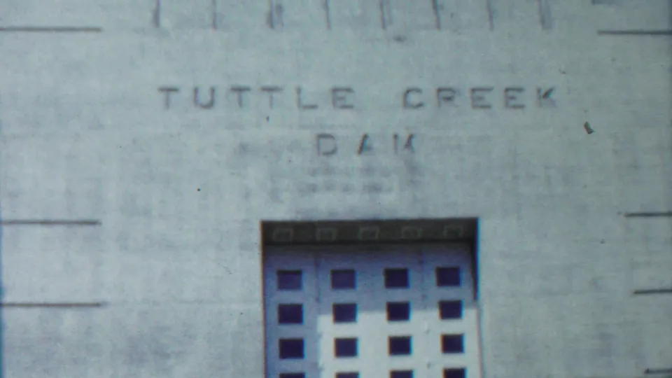 1959 Kansas home-movie view of Tuttle Creek Dam lettering above a large gridded gate set into the concrete wall.