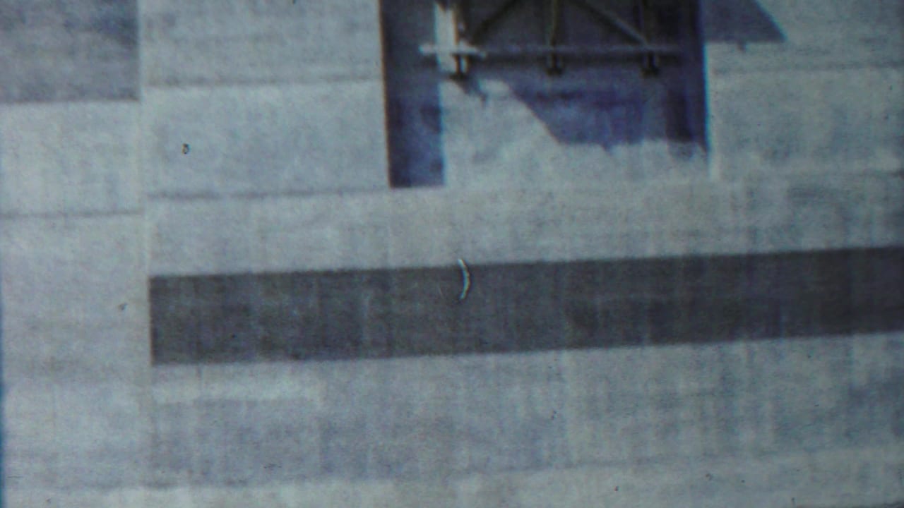 Concrete building detail in Saint Francis, Kansas, with a raised platform, dark horizontal opening, and weathered 8mm color.