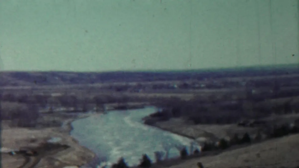 Wide 1959 8mm view near Saint Francis, Kansas, looking over a winding river through open fields and bare trees.