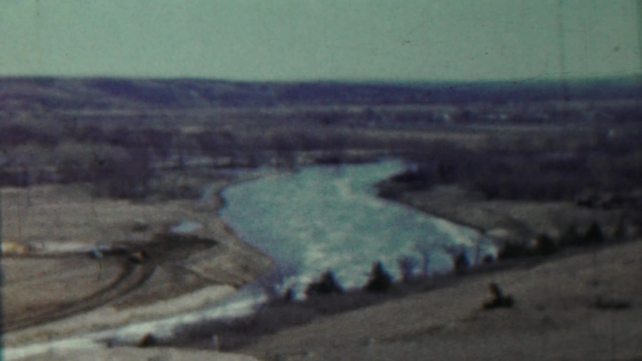 1959 Saint Francis, Kansas frame with a broad river bend, open fields, bare trees, and a hazy rural horizon.