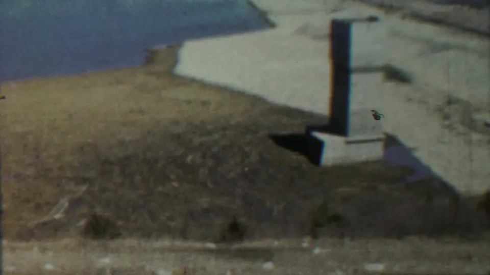 1959 Saint Francis, Kansas 8mm frame showing a pale column near a water edge, dry dirt, and sparse vegetation.
