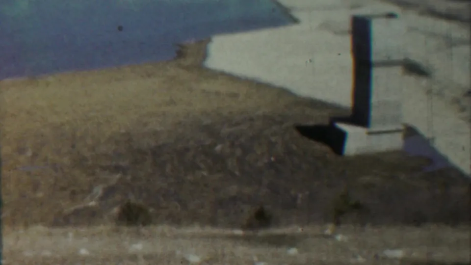 A slightly shifted 8mm view shows the column, its shadowed base, dry foreground, and calm water at Saint Francis, Kansas.