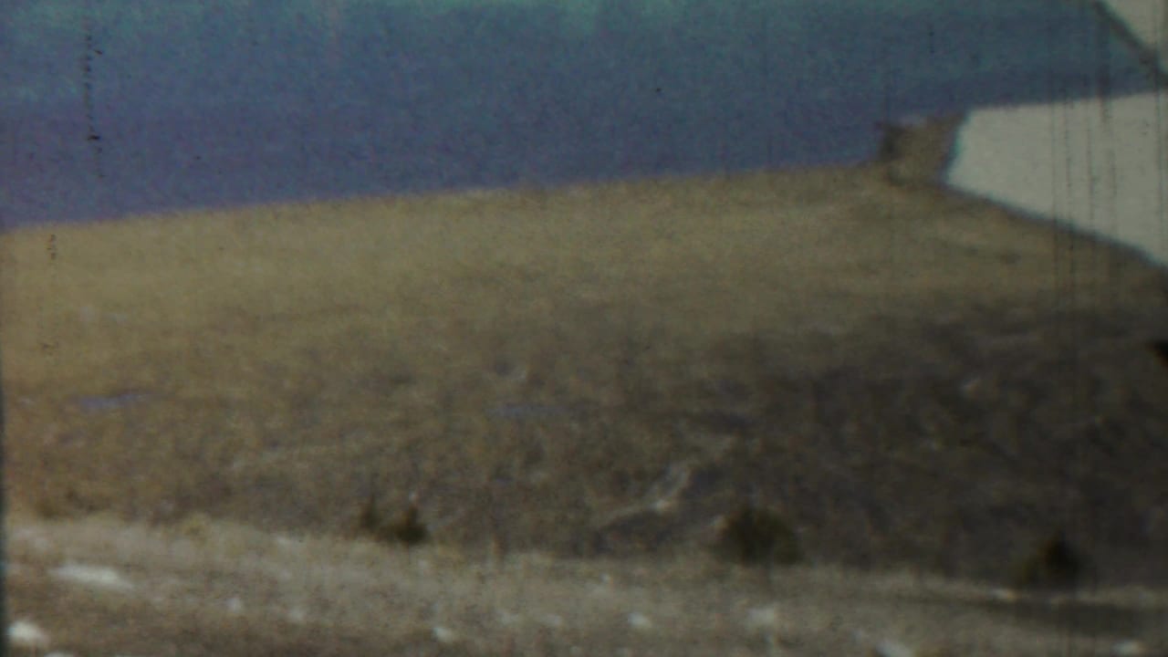 Wide dry field with blue sky and a partial white structure near the upper right edge.