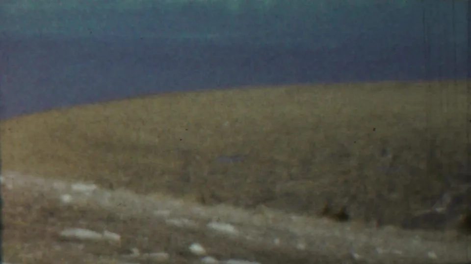 1959 8mm home-movie frame from the Saint Francis, Kansas metadata showing a blurred waterside shoreline and low land under blue sky.