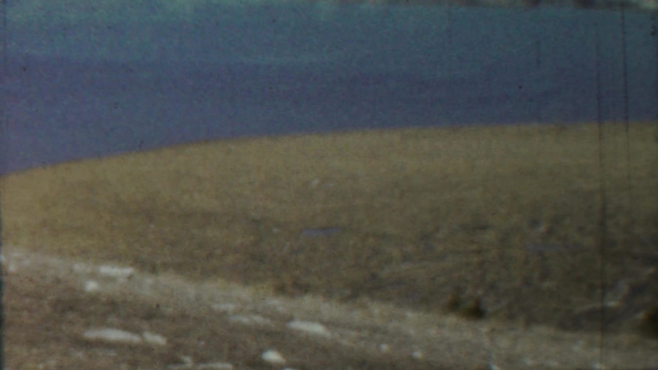 Distant land and shoreline across a calm body of water, seen in soft color.