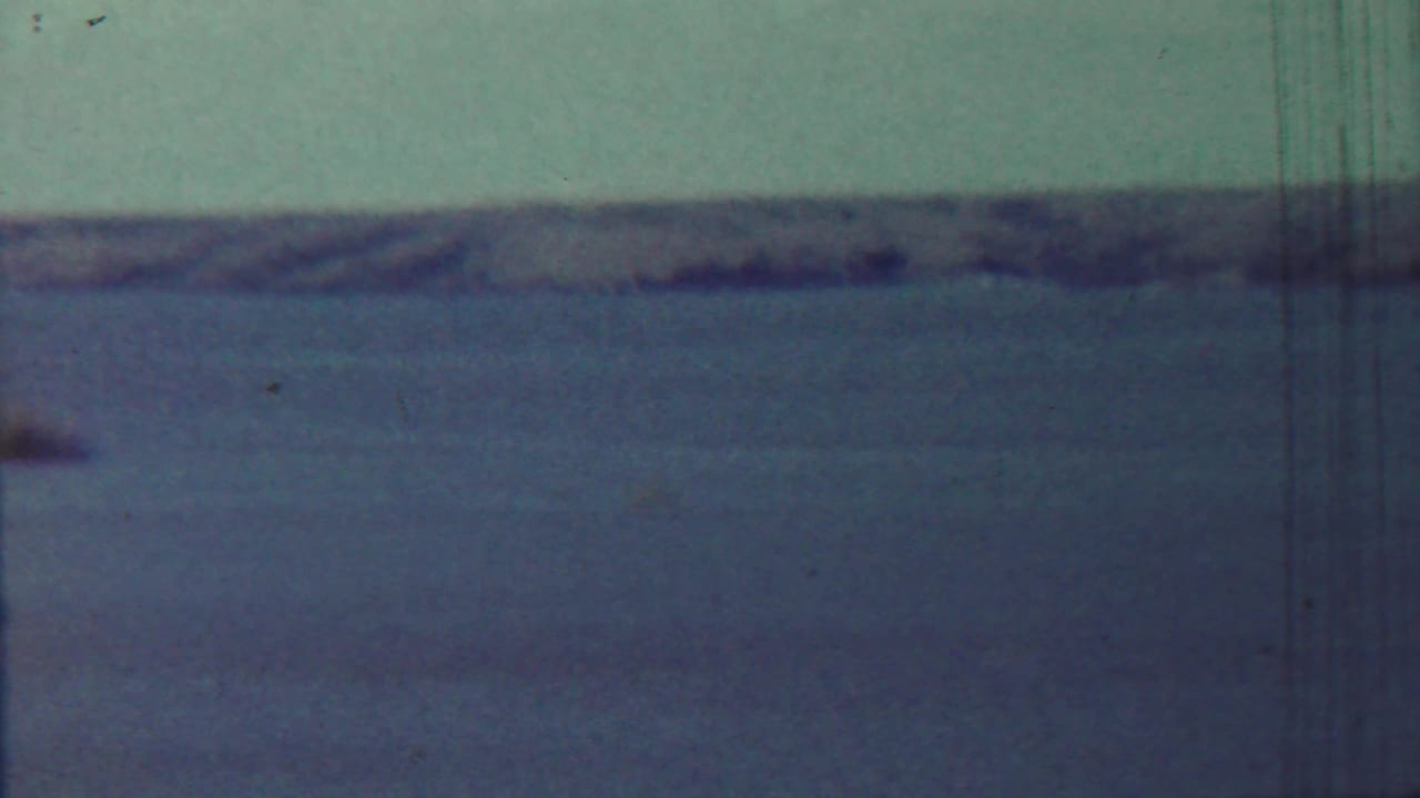 Open water and distant shoreline with a small indistinct speck near the horizon.