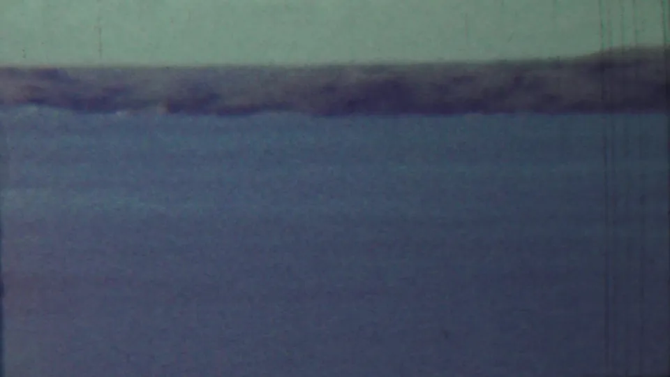1959 Saint Francis, Kansas 8mm frame showing broad water, muted sky, and a soft dark shoreline across the horizon.