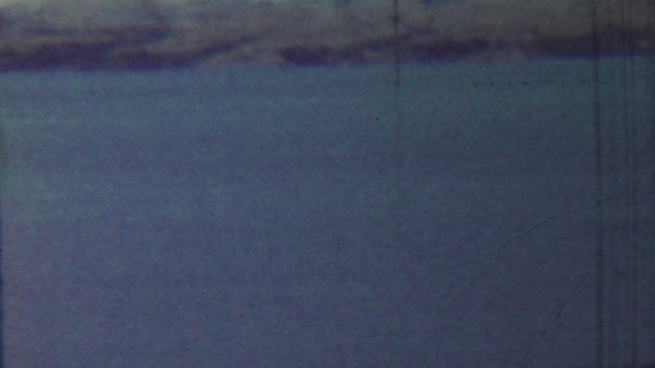 1959 Saint Francis, Kansas 8mm frame showing still water, a low distant shoreline, pale sky, and visible film wear.