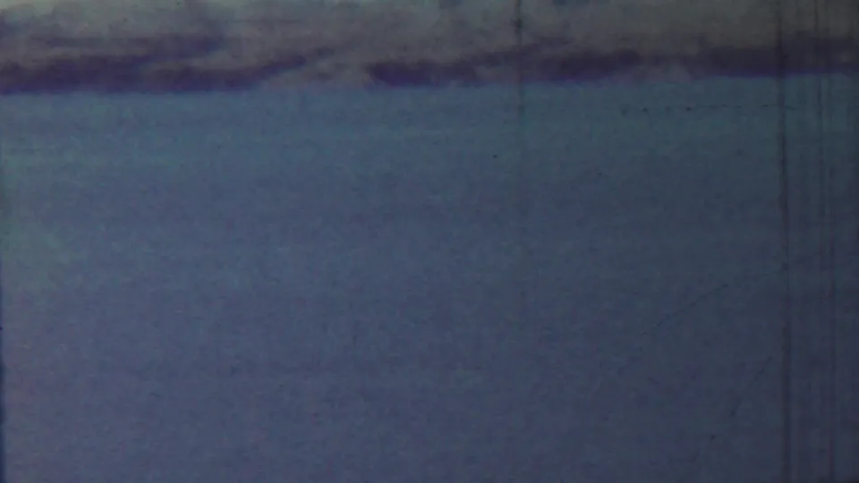 1959 Saint Francis, Kansas 8mm frame showing still water, a low distant shoreline, pale sky, and visible film wear.