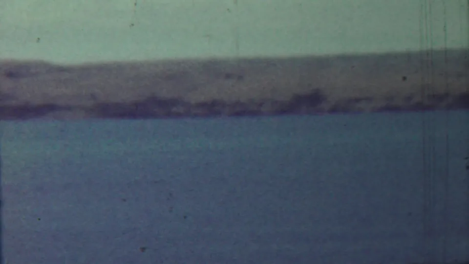 1959 Saint Francis, Kansas 8mm still of a low riverbank or shoreline across calm water under a pale sky.