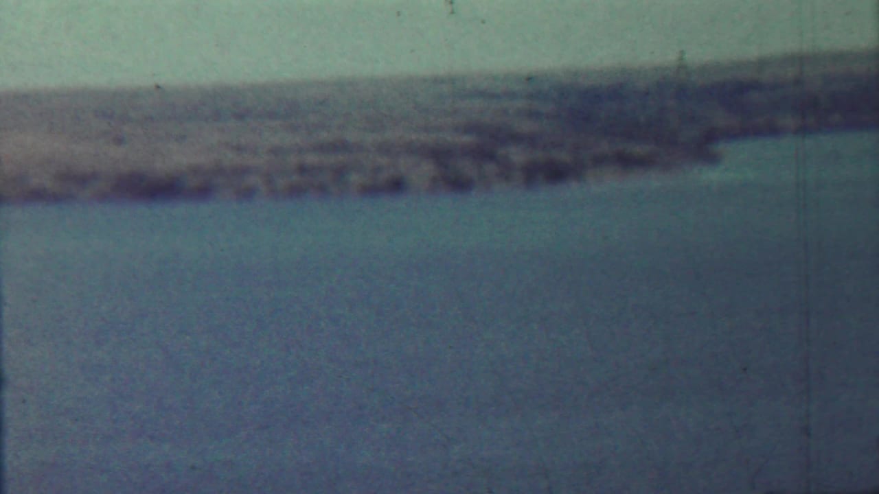 Calm water fills the foreground with a low, blurred shoreline in the distance.