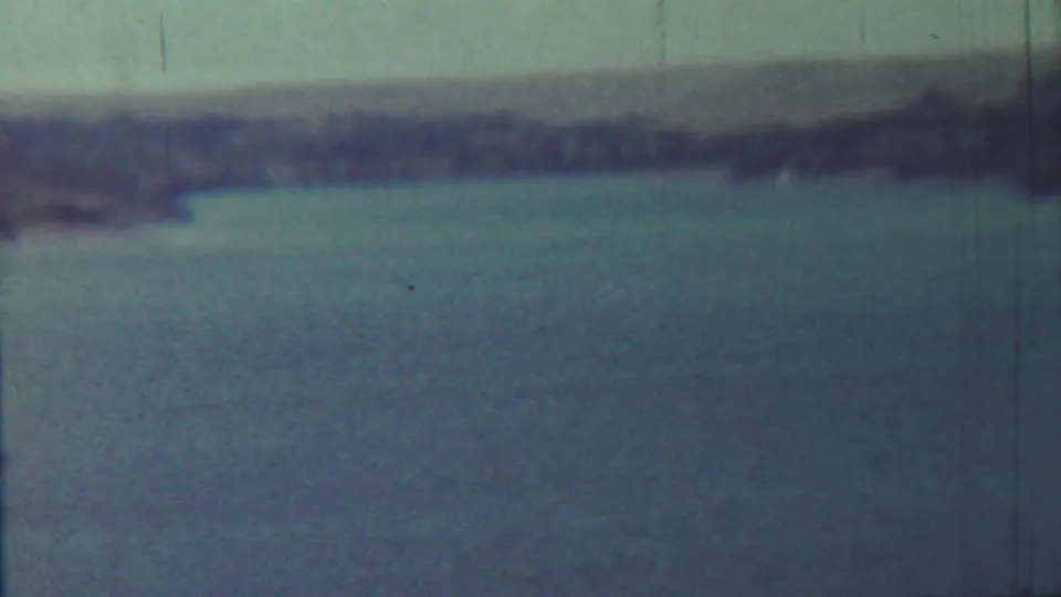 Final sampled 8mm frame showing calm water near Saint Francis, Kansas metadata, with a hazy shore and aged film texture.