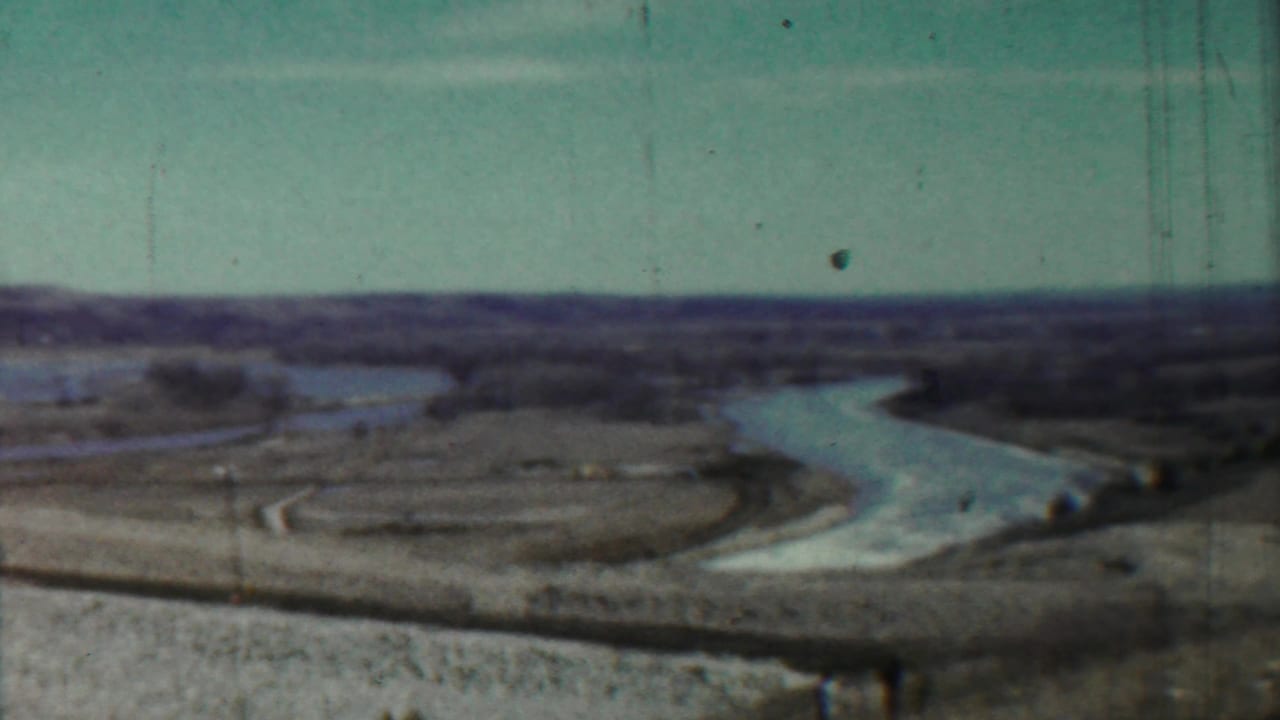Wide rural river bend with bare banks and distant horizon.