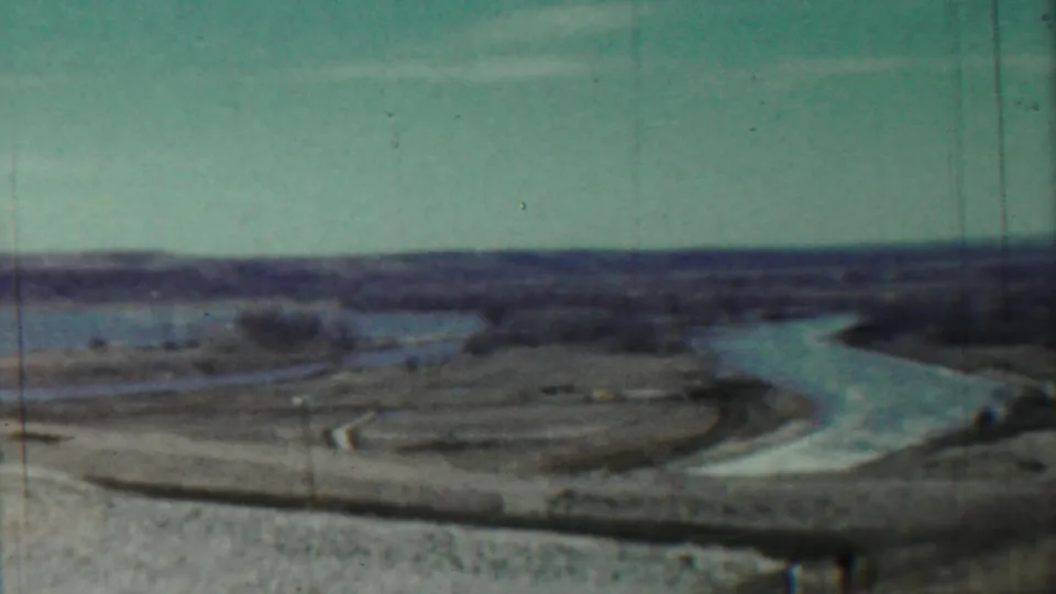 1959 Saint Francis, Kansas frame showing a soft, teal-tinted view of a river channel cutting through rural fields.