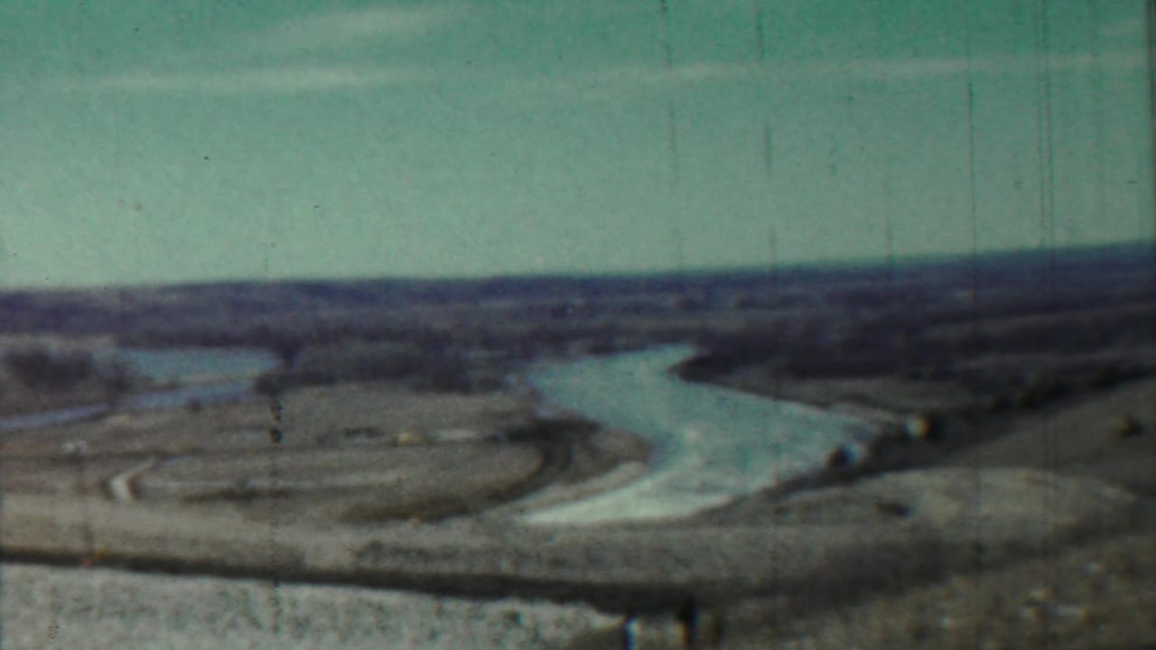 Hazy river winding through flat open land under a pale sky.