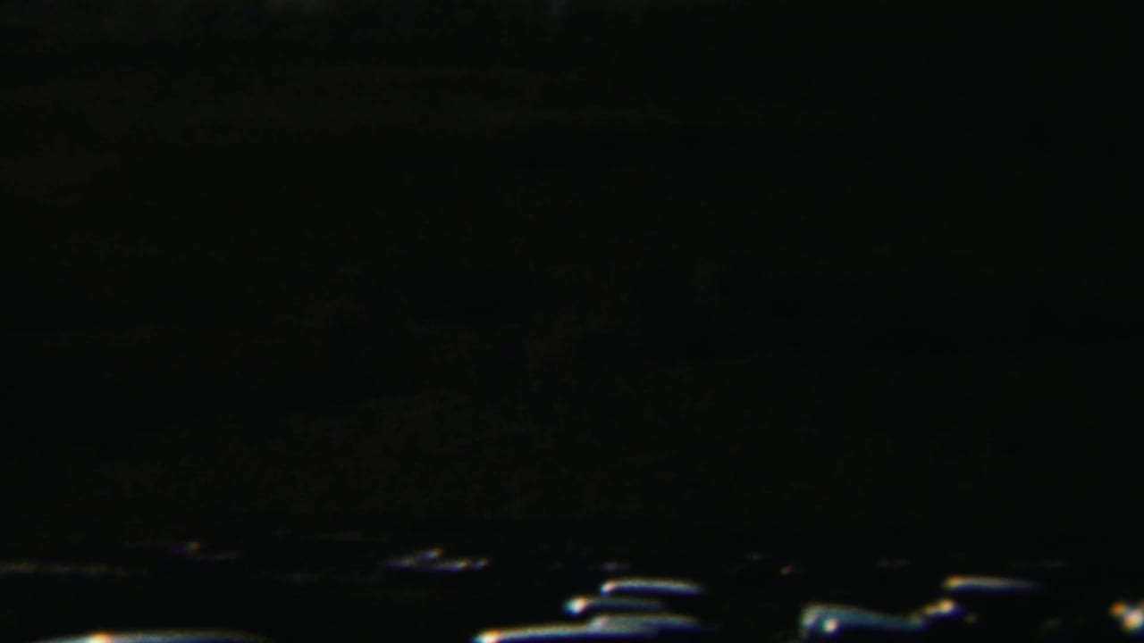 Very dark frame with faint horizon and small bright shapes near the lower edge.