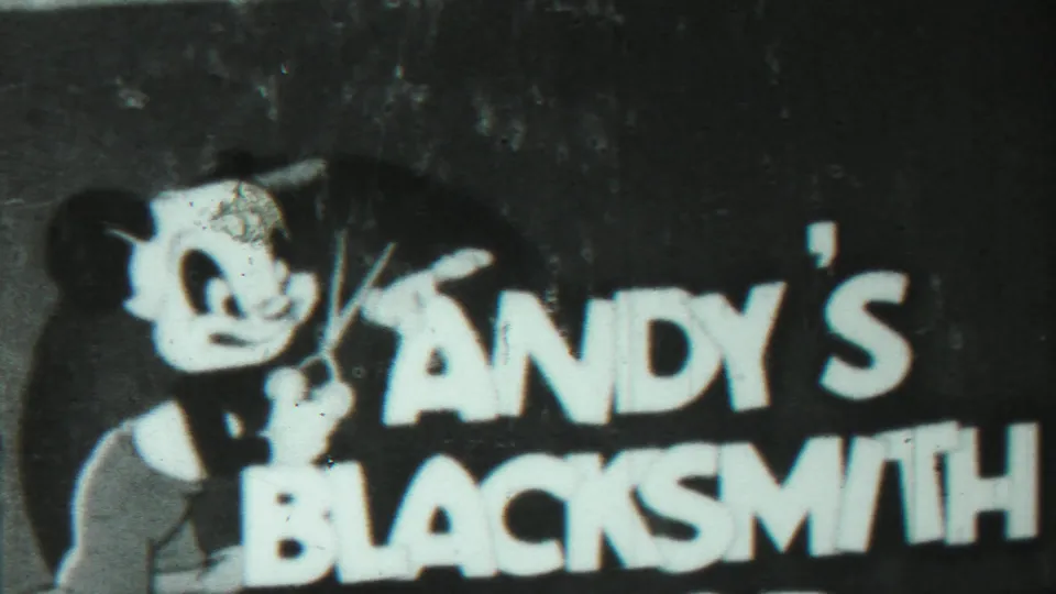 Another photographed Andy's Blacksmith card repeats the cartoon figure and bold text in grainy 8mm footage.