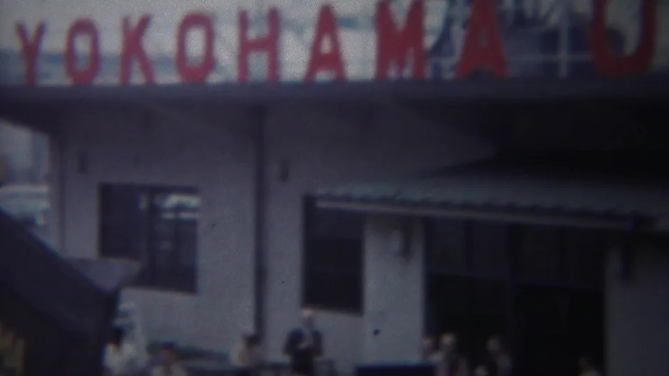 1954 Yokohama footage showing the red YOKOHAMA U.S. ARMY sign over a white port building with figures near the entrance.