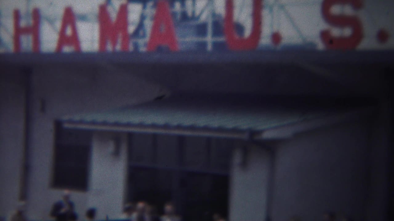 White port building with red sign letters, awnings, windows, and people near the entrances.