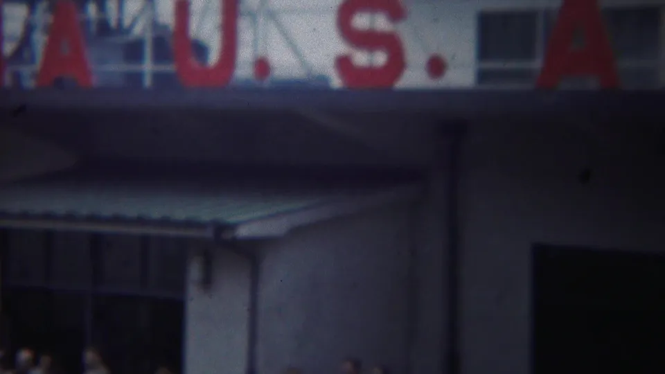Close 1954 view of the Yokohama port building showing red U.S. sign letters, a white facade, windows, and corrugated awnings.