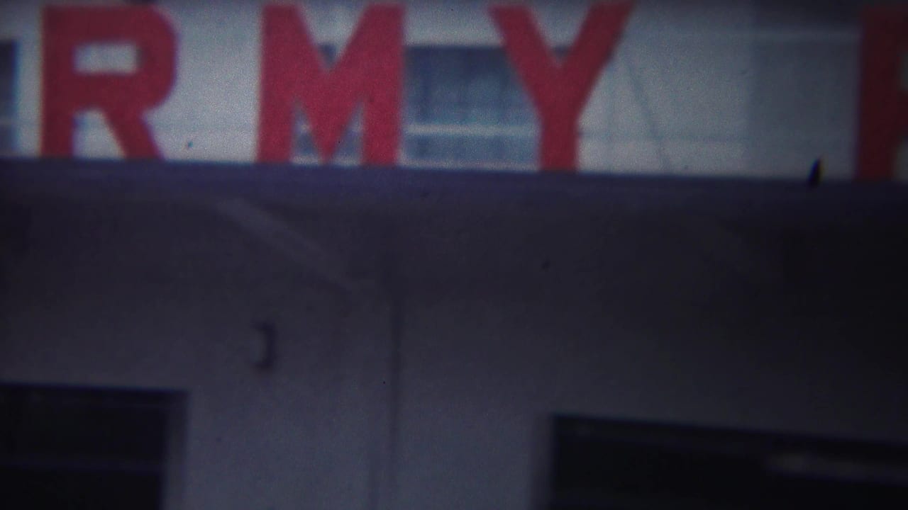 Blurred red letters continue across a building facade with windows behind.