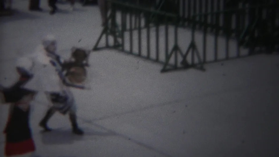 1954 Yokohama street festival frame with costumed performers moving past green barricades on pavement.