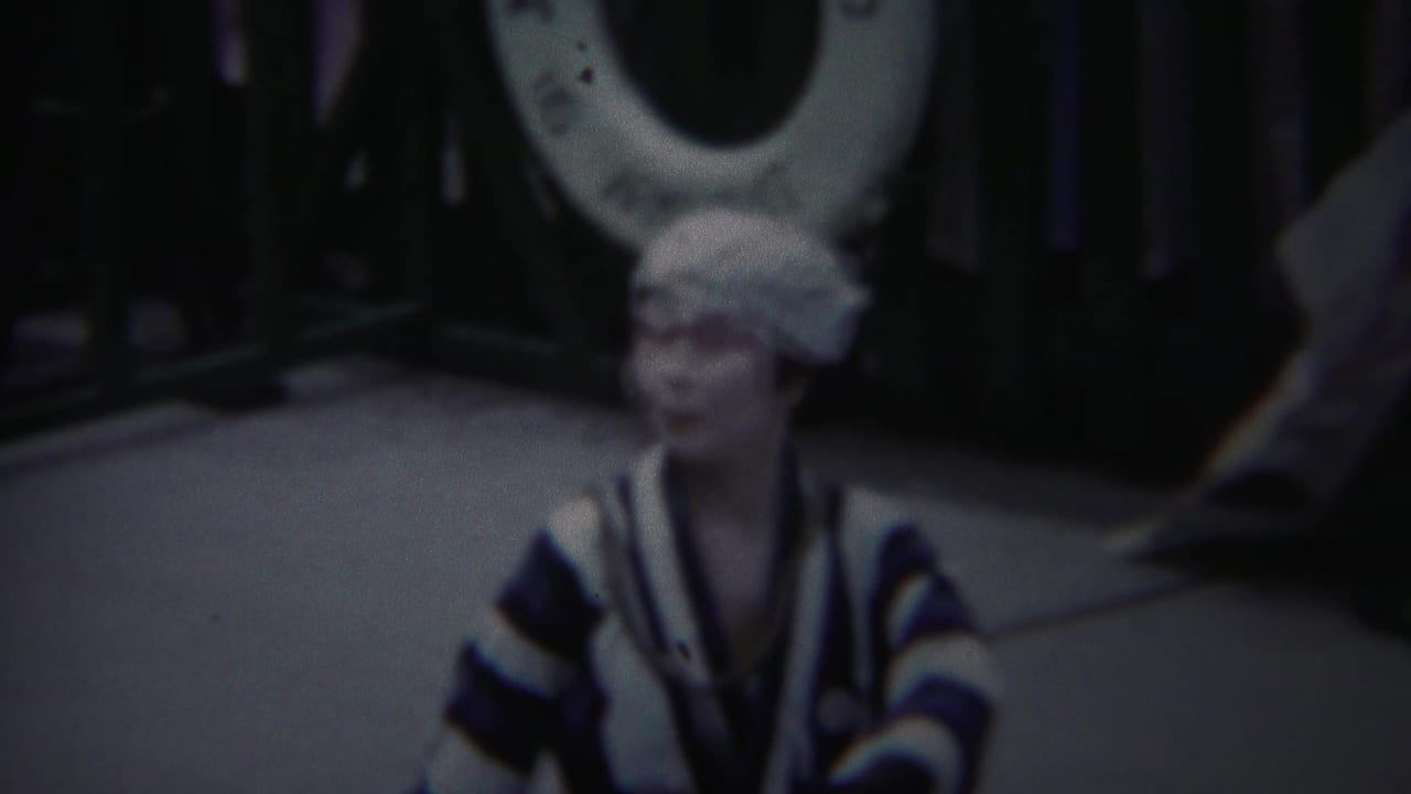 In 1954 Yokohama footage, the performer faces the camera in a blue-and-white striped kimono with one hand lifted.