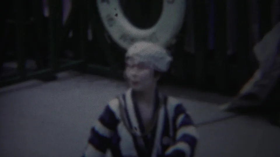 In 1954 Yokohama footage, the performer faces the camera in a blue-and-white striped kimono with one hand lifted.