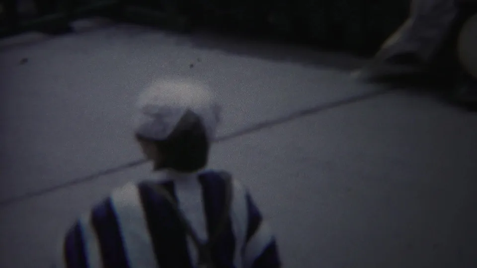 The performer turns away from the camera in 1954 Yokohama footage, showing the back of her striped kimono and white head covering.