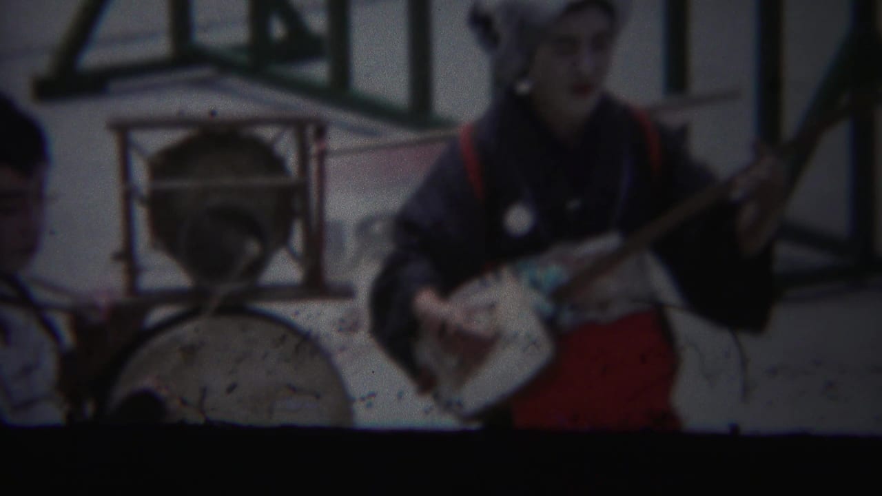 Soft 8mm frame from Yokohama in 1954 showing a traditional music performer beside a large drum.