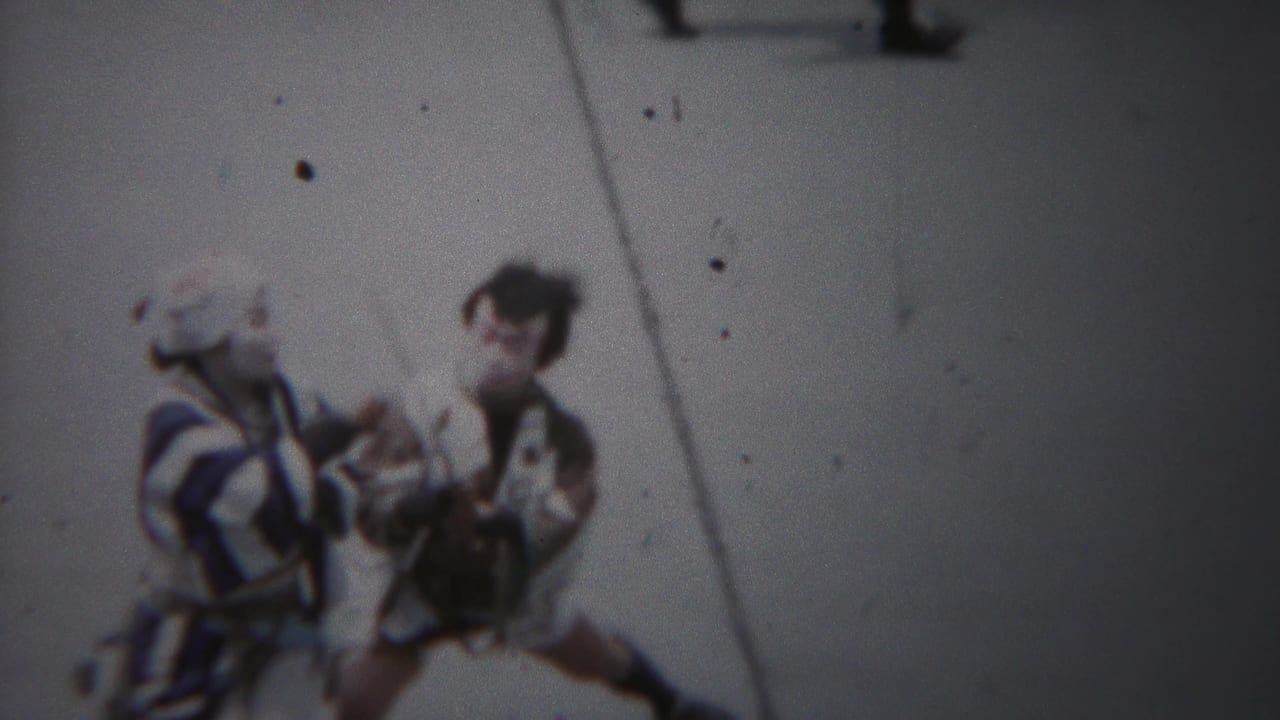 High-angle 1954 Yokohama home-movie view of two costumed performers with traditional instruments on pavement.