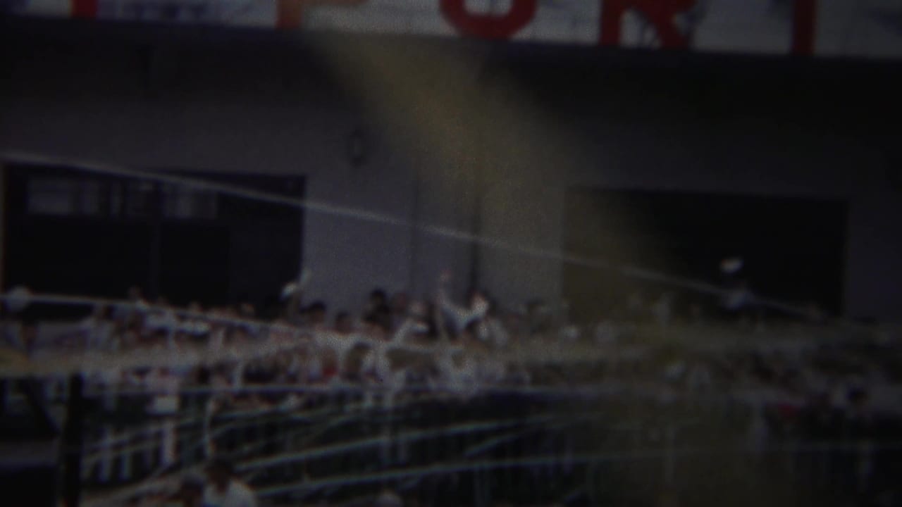 Yokohama 1954 parade or gathering view with spectators at railings in front of a large building with red lettering above.