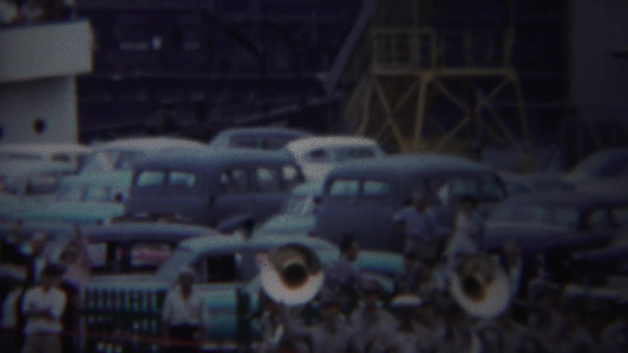 Yokohama 1954 frame showing brass players and a crowd among parked mid-century cars near an army port structure.